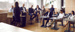 © Studio Romantic - Professional smart business woman conducts training seminar for diverse business people. Diverse group of business people sit in loft hall business center and listen to coach. Panorama.