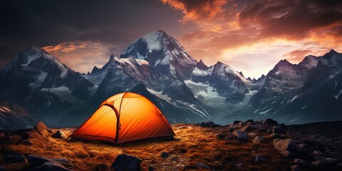 glowing orange tent camping in the mountains in front of majestic mountain range
