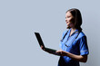 © Valerii Honcharuk - Female nurse using laptop, profile view on gray studio background