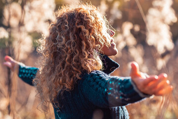 Back side view of woman enjoying sunset in golden field of grass opening outstretching arms alone. People and environment, Healthy lifestyle concept female loving nature in outdoor leisure activity