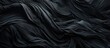 A dark black cloth is draped over a neatly made bed, creating a sleek and minimalist look in the room. The cloth hangs elegantly over the sides of the bed, adding a touch of sophistication to the