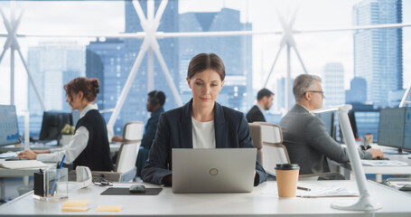 Poster - Professional Female Business Development Manager Typing On Laptop Computer In Bright Skyscraper Office In Downtown. Successful Caucasian Woman Working With Annual Reports In Diverse Workspace.