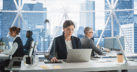 Poster - Professional Female Business Development Manager Typing On Laptop Computer In Bright Skyscraper Office In Downtown. Successful Caucasian Woman Working With Annual Reports In Multiethnic Workspace.