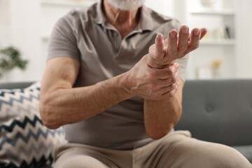 Wall Mural - Arthritis symptoms. Man suffering from pain in wrist at home, closeup