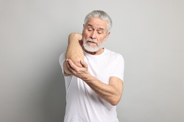 Wall Mural - Arthritis symptoms. Man suffering from pain in elbow on gray background