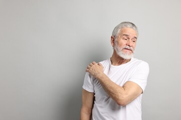 Wall Mural - Arthritis symptoms. Man suffering from pain in shoulder on gray background, space for text