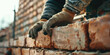 Closeup Hands Adjusting Bricks in Wall. Worker's hand placing a brick on a crumbling wall.