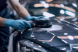 a hand polishing a car body using a portable polishing machine