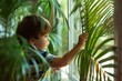Little toddler boy standing near a window and touching house plant at home. Baby discovering the world.