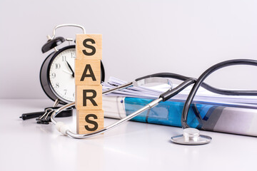 Poster - text SARS is written on wooden cubes near a stethoscope on a paper background. medical concept. SARS - short for Severe acute respiratory syndrome