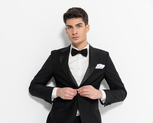 Wall Mural - cool fashion businessman looking forward and buttoning black tux