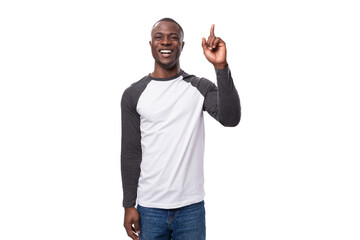 Wall Mural - close-up portrait of a young handsome american guy with a short haircut in a sweatshirt pointing with his hand at the empty space