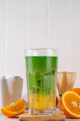 Wall Mural - Orange Matcha Lemonade, Cold asia fruit cocktail with green matcha and orange citrus drink on white background, copy space