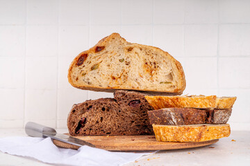 Homemade freshly baked sourdough bread. Craft homemade baked bread, rye and white, on a white table. The girl’s hands in the picture are cutting freshly baked fragrant bread copy space