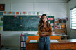 © Lux Images - Portrait of a Latin teacher posing and looking at the camera in an empty classroom with a chalkboard background.
