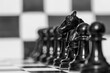 Detalle de  la figura del caballo entre los peones de un tablero de ajedrez, en blanco y negro