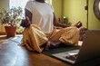 © Marko Geber - Woman meditating on yoga mat with laptop at home