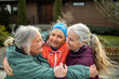 © Marko Geber - Group of joyful active senior women hugging and smiling outdoors