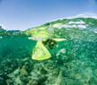 © ADDICTIVE STOCK - A dynamic underwater perspective of anonymous snorkeler's yellow fins amidst a burst of air bubbles over a pebbled sea floor in sunlit waters