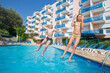 © Pavel Losevsky - Happy boy and girl in swimsuit jump in blue pool near hotel at summer day