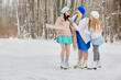 Three smiling women skate at outdoor skate rink in winter park