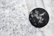 Hockey puck lies on snow-covered ice surface at outdoor skating rink