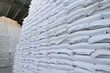 Many new plastic white sacks with goods are in big warehouse