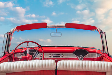 Wall Mural - Driver view of a red vintage classic open American cabriolet car in front of a sunny blue sky