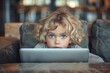 A child with a bored expression sitting with a laptop