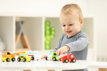 Sticker - Children toys. Cute little boy playing with toy cars at white table in room, space for text