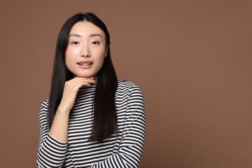 Wall Mural - Portrait of smiling woman on brown background. Space for text