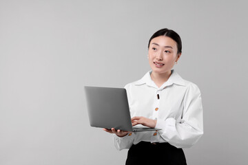 Poster - Portrait of smiling businesswoman with laptop on grey background. Space for text