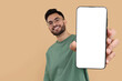 © New Africa - Happy man holding smartphone with empty screen on beige background, space for text