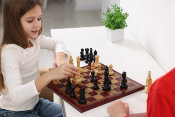 Wall Mural - Cute children playing chess at table in room