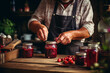 Close-up of elderly man's hands canning ripe berries in jars on a rustic kitchen table