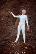 Full length portrait of young hairless girl with alopecia in white futuristic suit holding handful of barren soil thoughtfully, highlighting potential for coexistence between humanity and environment