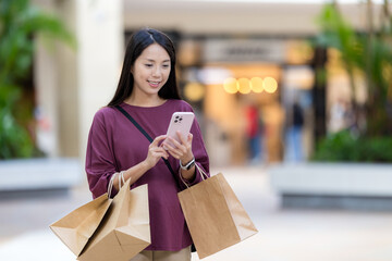 Poster - Woman use mobile phone with shopping bag at the plaza