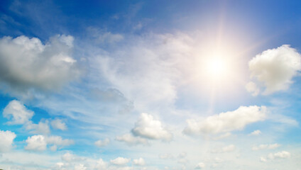 Wall Mural - There are white cumulus clouds and a bright sun in the blue sky.