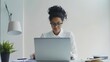 The young businesswoman smiles as she works on her laptop in the office