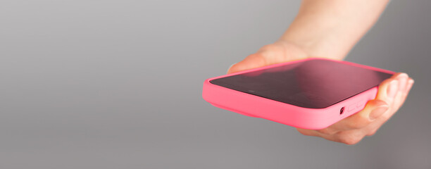 Poster - Hand holding mobile phone in pink case, banner background with copy space for text