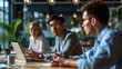 © MP Studio - Diverse group of four young professionals or friends, gathered around a laptop at a modern workspace, collaborating or discussing