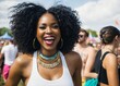 a woman with a large afro smiles at the camera while standing in front of a crowd of people at a music festival