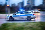 Fototapeta Miasto - Radiowóz polskiej policji na sygnałach alarmowo szybko jedzie przez miasto na interwencję.
