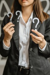 Poster - A woman in a business suit holding up question marks. Suitable for business and education concepts.
