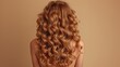 Portrait of a beautiful girl with luxurious curly long hair. Back view. Care, and hair and skin care products. Copy space on the left side