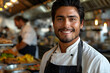 Smiling young Hispanic chef standing in the kitchen of a luxury restaurant, space for text