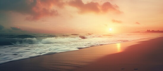 Wall Mural - A hazy image of a beach at sunset with the sun peaking through the clouds, creating a mesmerizing atmosphere over the fluid water and natural landscape