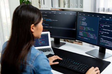 Young Asian in IT developer creating with typing online information on pc with coding program data of website application, wearing jeans shirt. surrounded by safety analysis two screens. Stratagem.