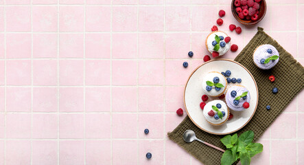 Wall Mural - Plate of delicious cupcakes with blueberries, raspberries and mint on pink tile background