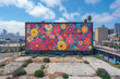 A colorful and large mural adorns the side of a building, showcasing various vibrant patterns and designs, mockup